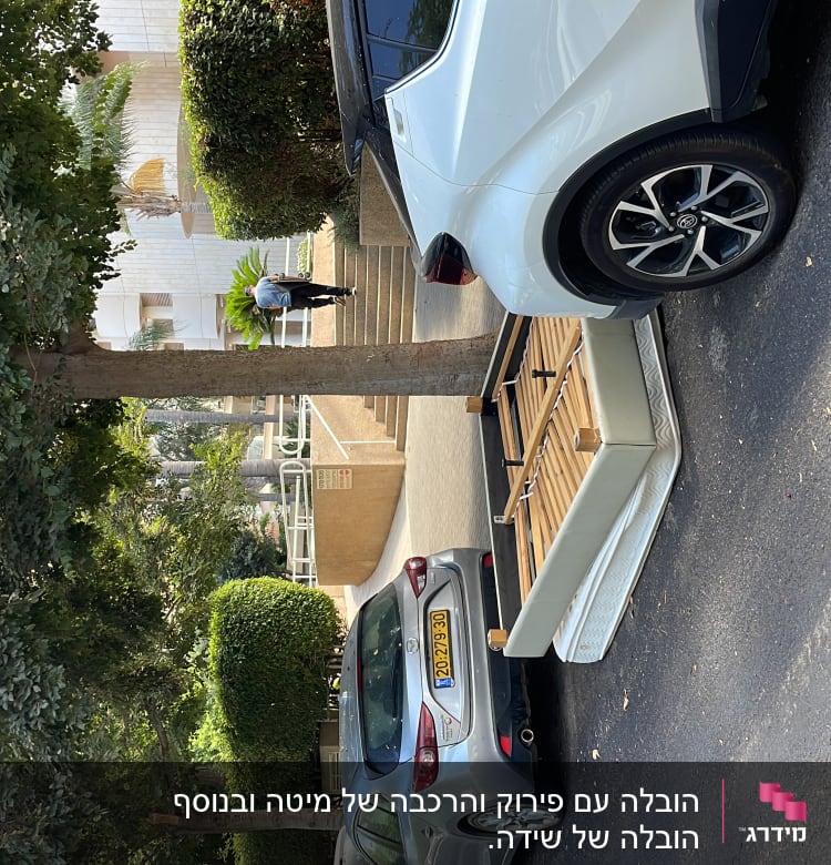 מכונית לבנה עם נגרר להובלה חונה ברחוב